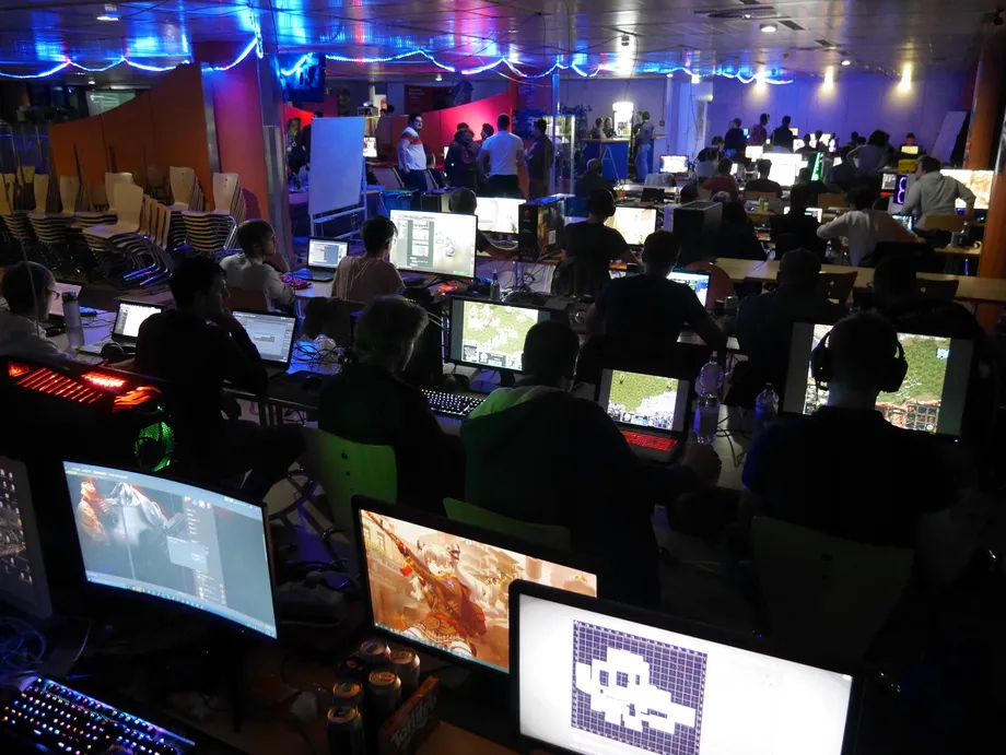 LAN-Party Impression, mehrere Tischreihen mit an PCs spielenden Menschen